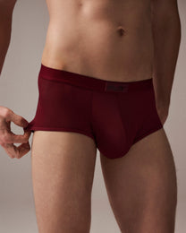 Model wearing the deep red BSZN sheer mesh trunk, front view demonstrating side stretch