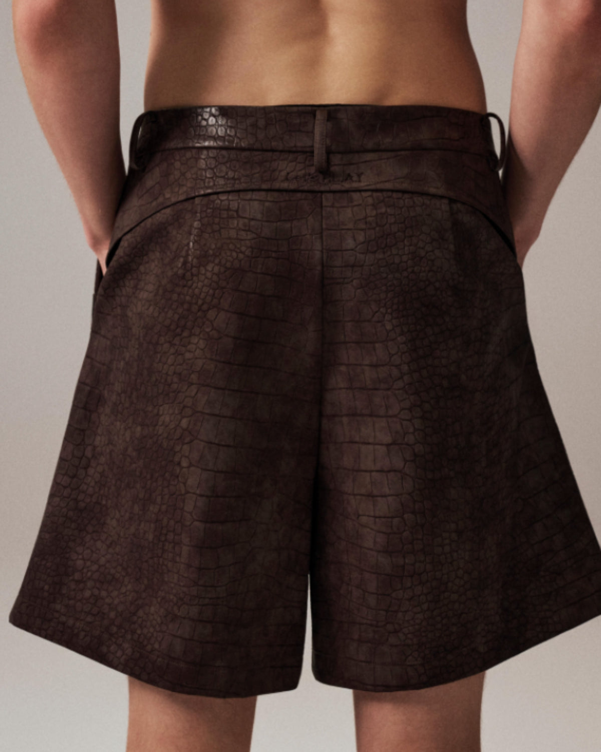Model wearing the brown BSZN reptile-embossed tailored shorts, rear three-quarter view