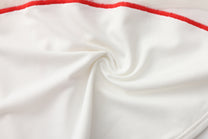 Close-up of smooth white stretch fabric and red contrast seam