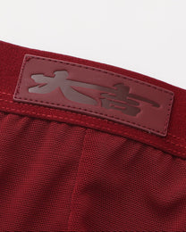 Close-up of the tonal good-fortune character patch at the deep red waistband