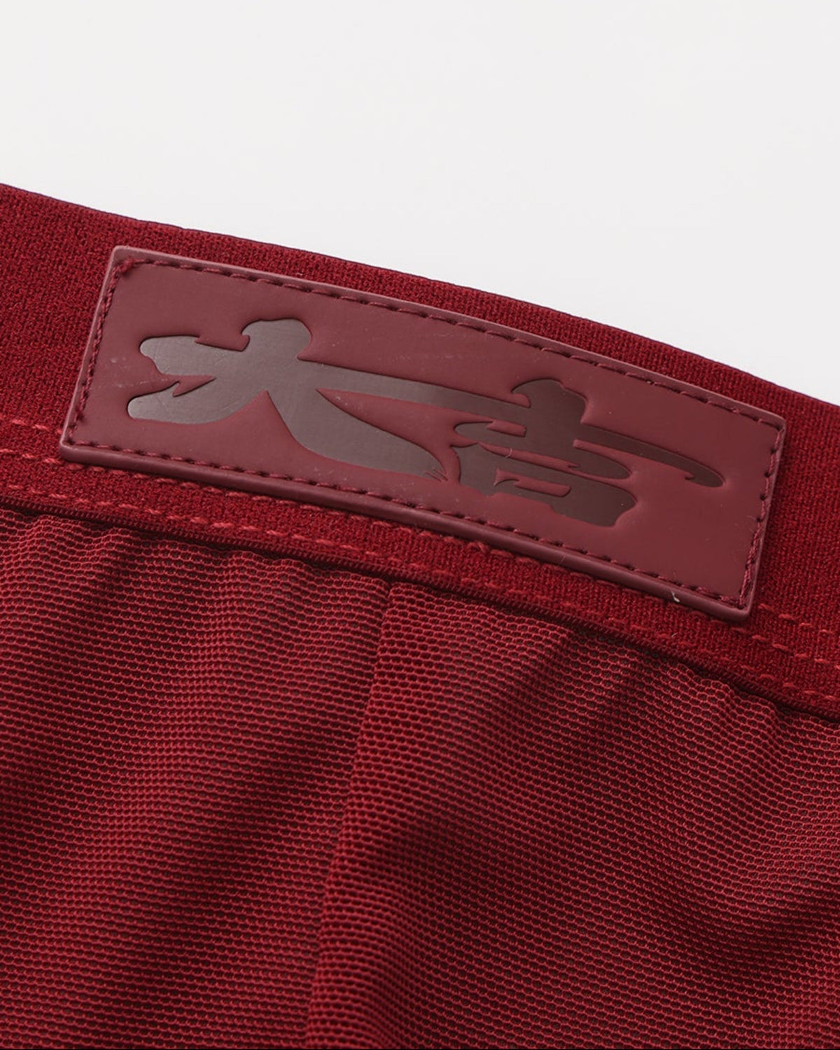 Close-up of the tonal good-fortune character patch at the deep red waistband