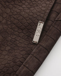 Close-up of the silver-tone BSZN side plaque on the reptile-embossed brown shorts