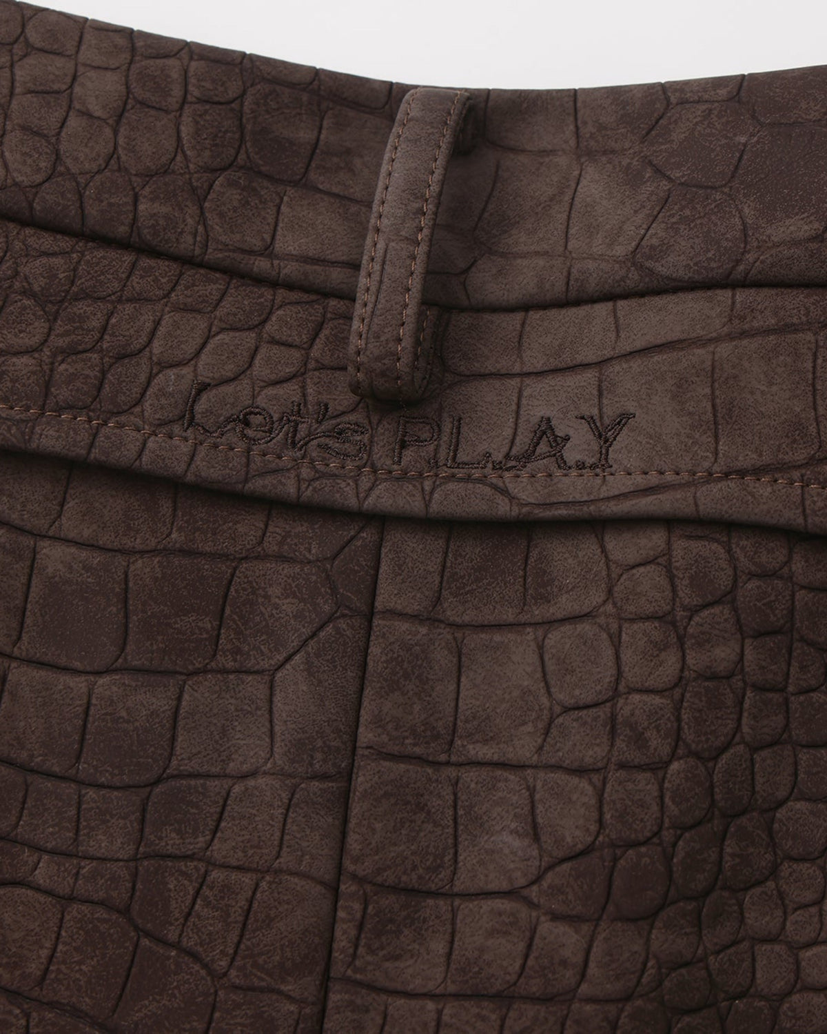 Close-up of the rear belt loop and tonal LET'S PLAY lettering on the brown shorts