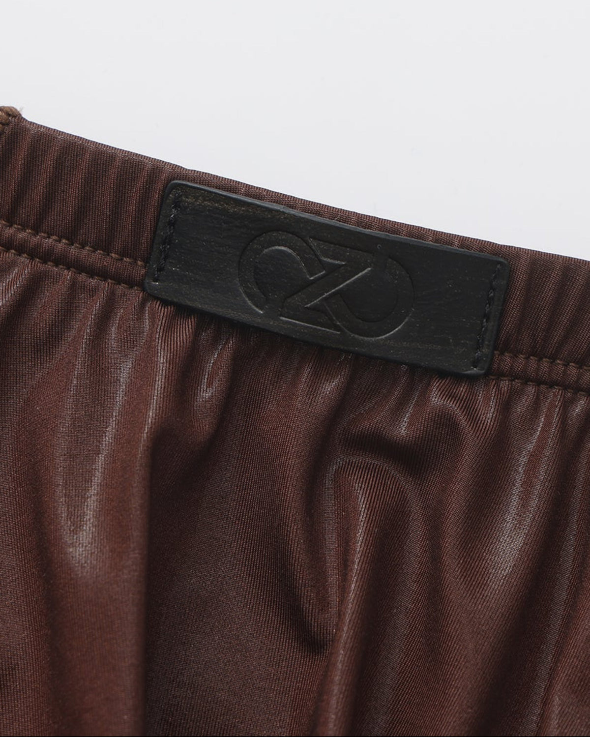 Close-up of the dark tonal BSZN logo patch at the brown brief waistband
