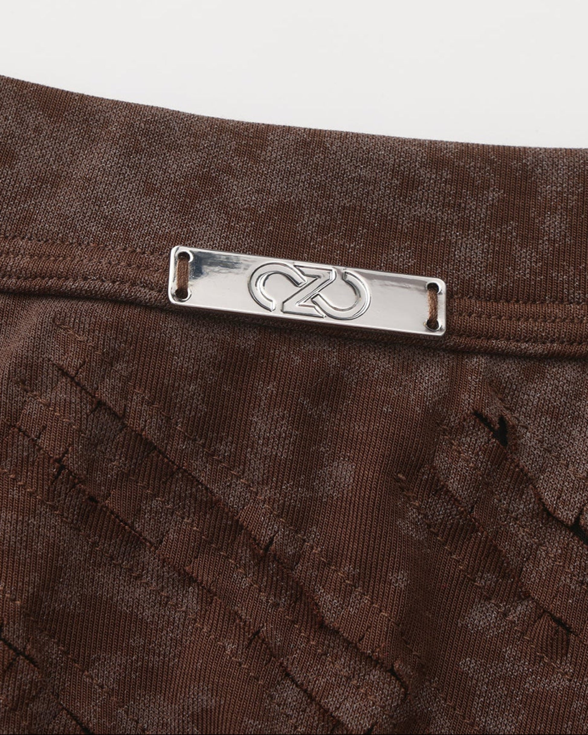 Close-up of the waistband plaque and front-cutout construction on the brown BSZN trunk