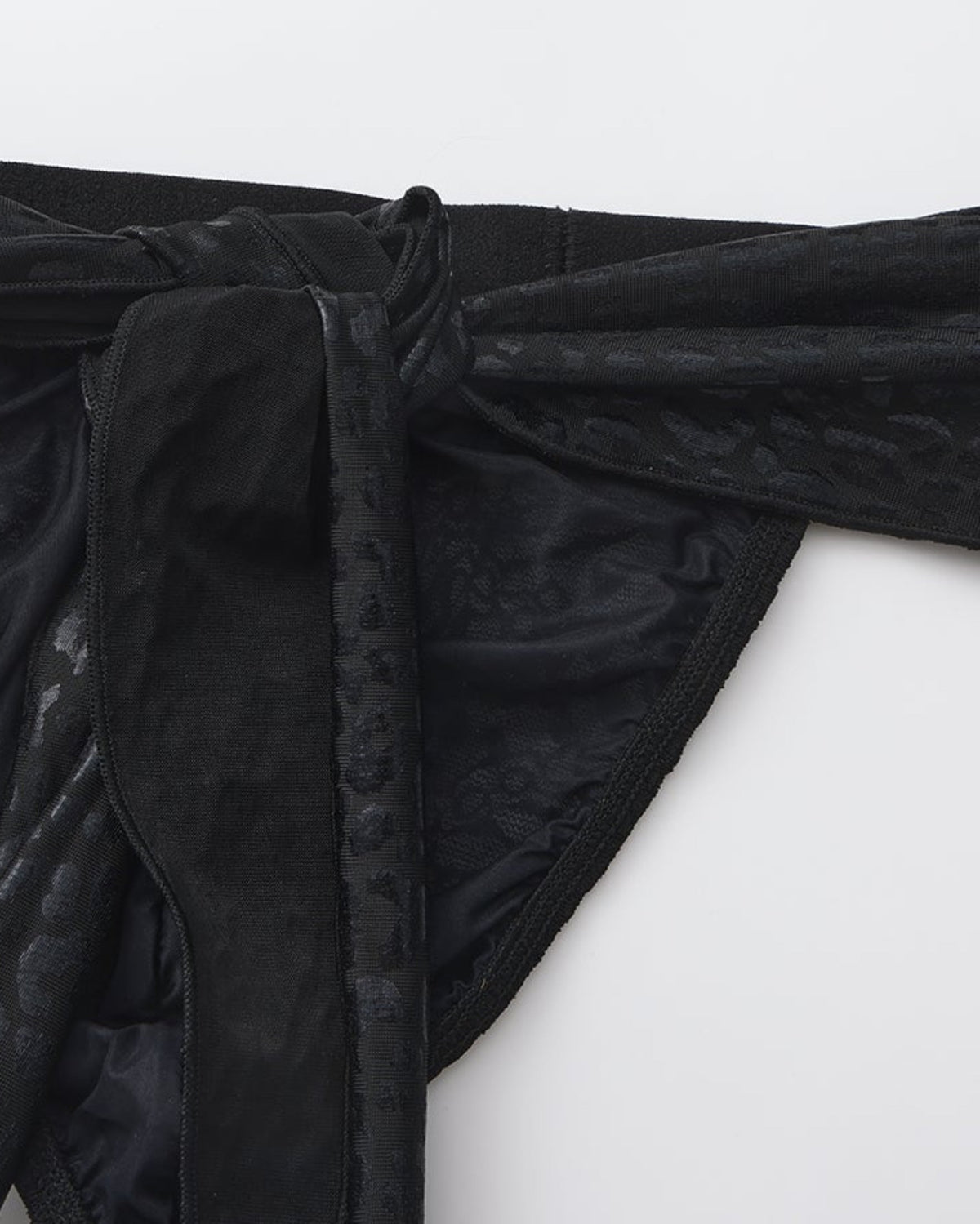 BSZN Draped scarf ties over patterned lace, close-up.